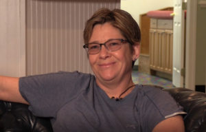 Angela Ogden sitting on a couch in her home.